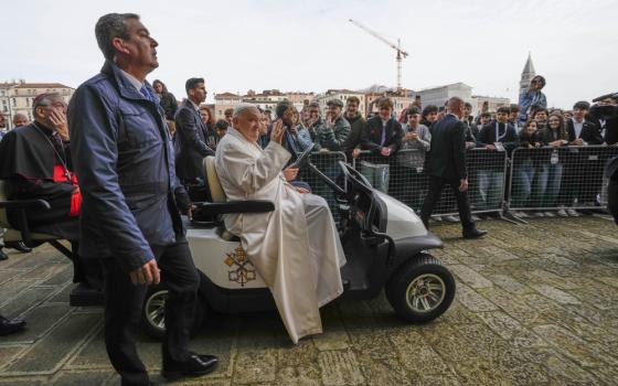 Pope Francis sits in mini popemobile and waves to people